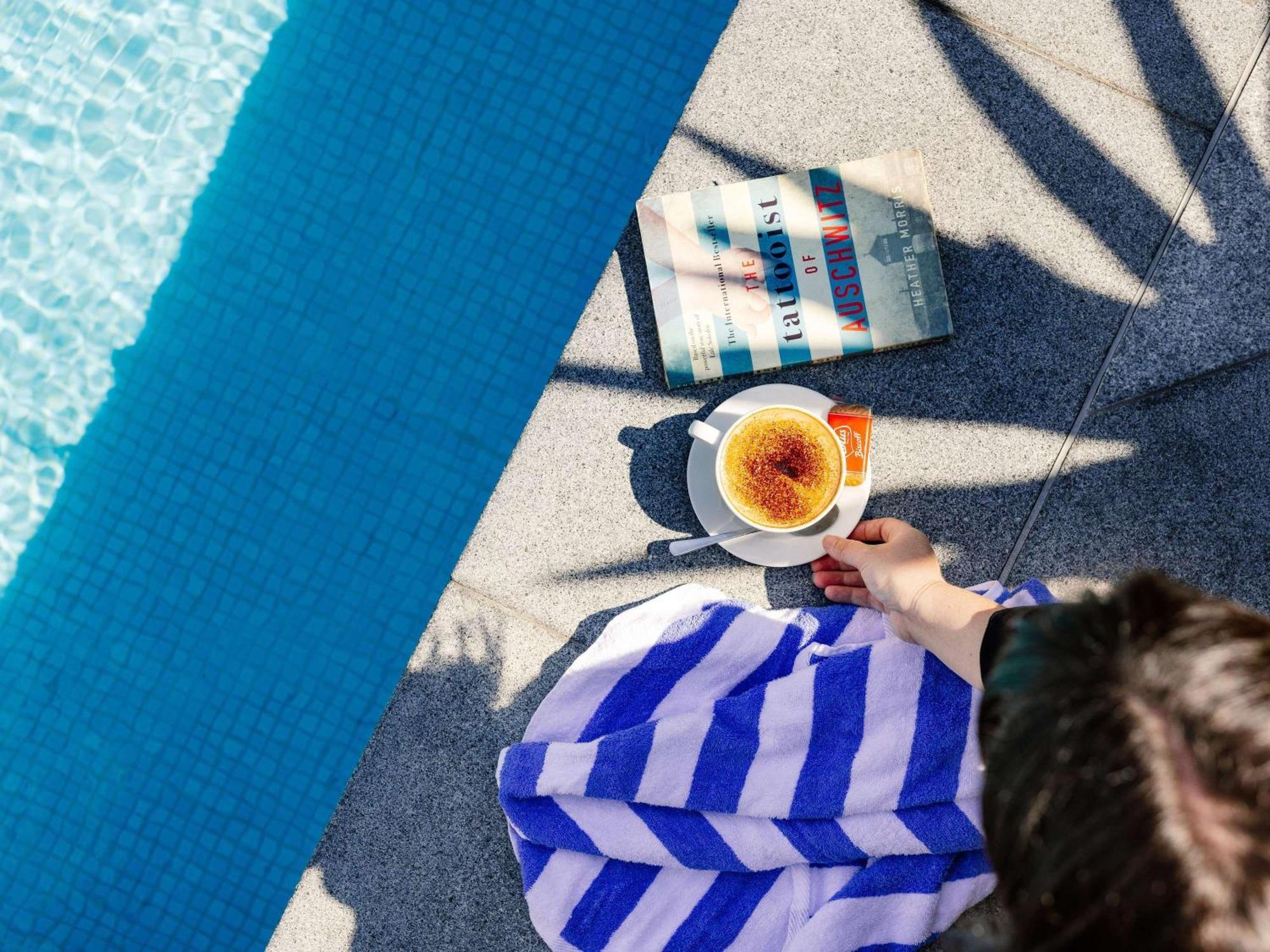 Pullman Brisbane Airport Hotell Exteriör bild A woman reading a book by the pool